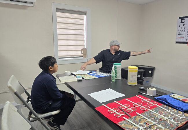 A volunteer eye doctor fitting a boy for glasses at the Medical Mission Brigade