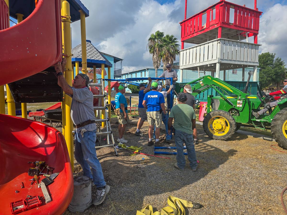 Volunteers raising playground framework with a tractor on the Rio Bravo Ministries campus