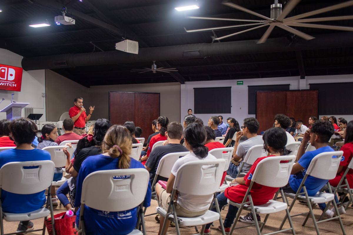 A pastor speaking to a room full of young people at a camp on the campus